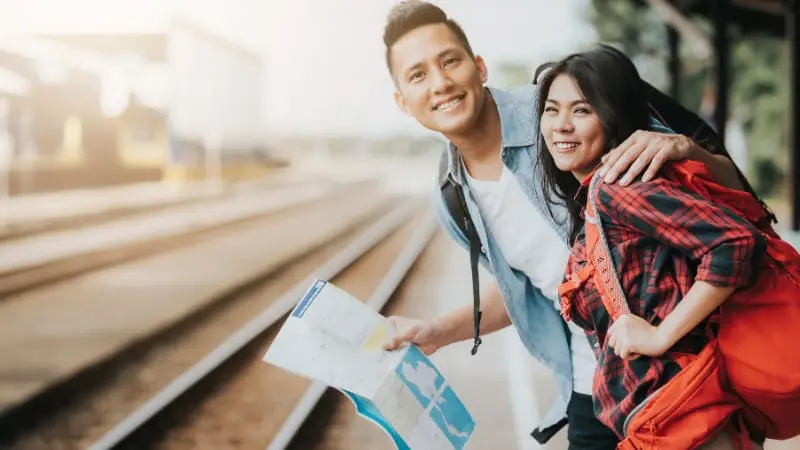 Couple with a map at a train station, planning their visit to beautiful train destinations close to Amsterdam.