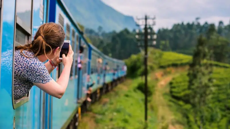Tourist taking photos from a train window, highlighting scenic train destinations one hour away from Amsterdam.