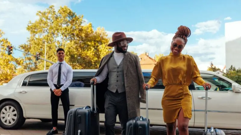 Stylish travelers with luggage beside a limousine, highlighting upscale transportation choices for exploring Doha.