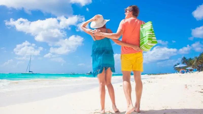 Couple embracing the sun and sand during their budget-friendly Barbados beach vacation.