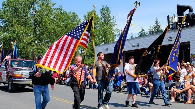 Celebrate Independence Day 2024 at a small-town parade with marchers proudly waving US flags.
