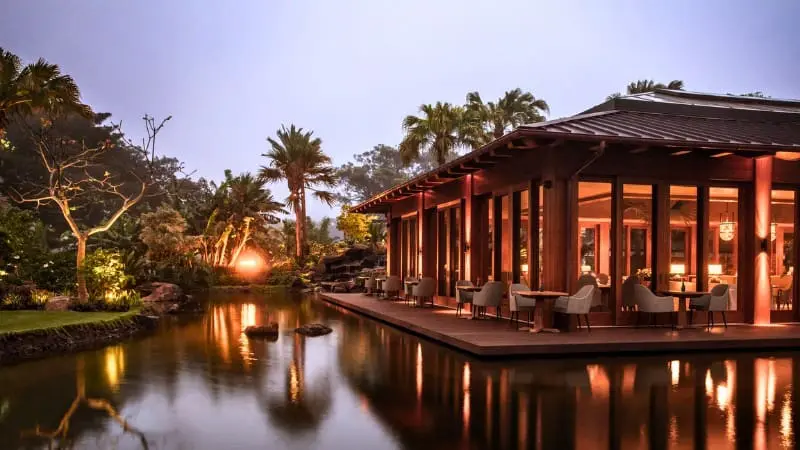 Romantic waterfront dining at adults-only Sensei Lanai resort lit up at night.
