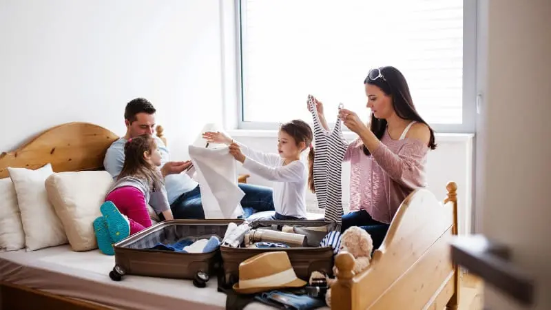 Family in the living room packs for a trip, preparing for Europe with kids travel.