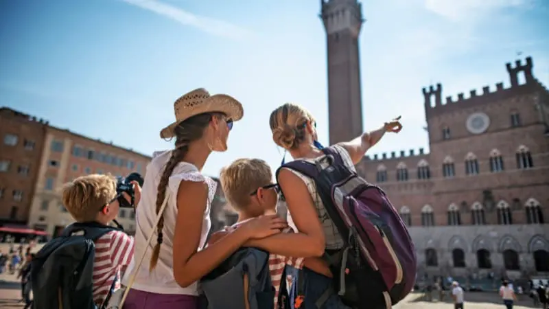 Family of tourists pointing at a famous medieval tower while traveling in Europe with kids.
