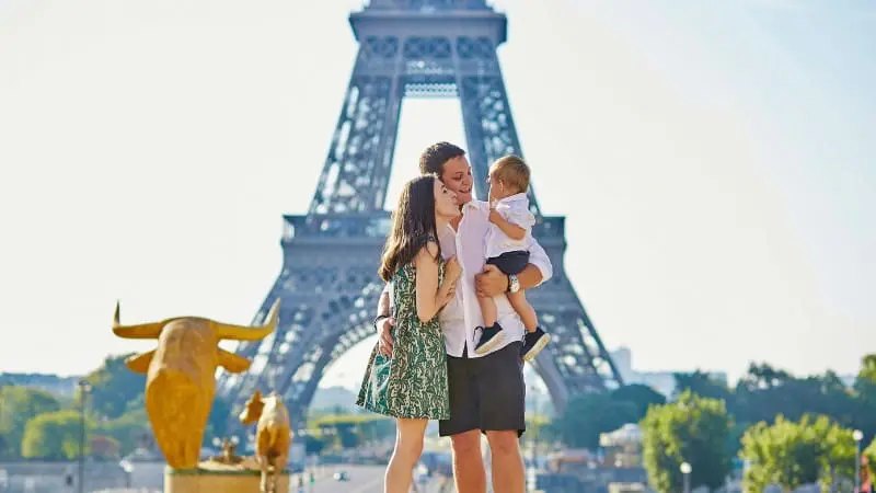 Parents and child creating memories in front of the Eiffel Tower during their Europe trip.
