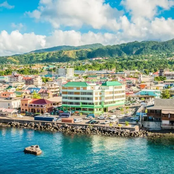 Living in Dominica offers stunning views of colorful houses, lush mountains, and the sea.