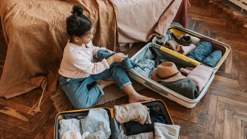 Young girl packs suitcase for a family vacation to Maui with kids, ready for adventure.