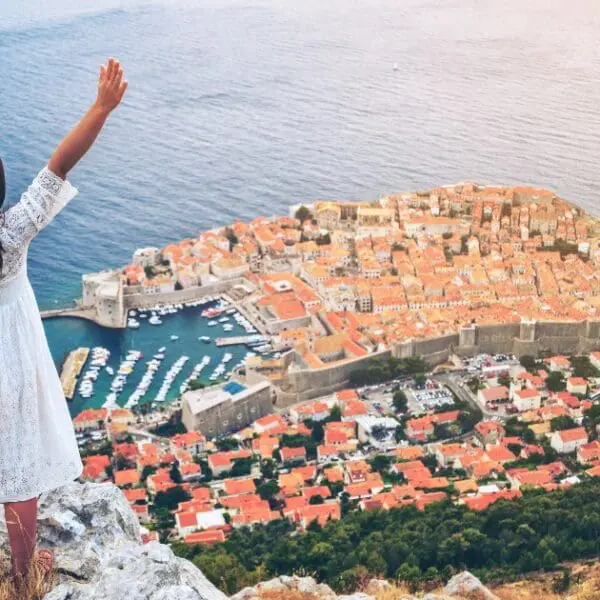 Woman celebrating Croatia itinerary success overlooking Dubrovnik and Adriatic Sea.