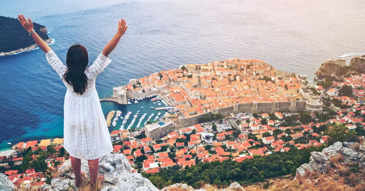 Woman celebrating Croatia itinerary success overlooking Dubrovnik and Adriatic Sea.