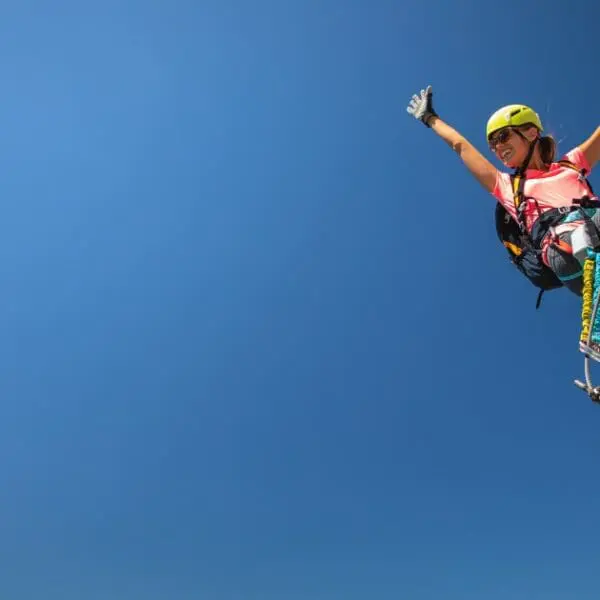 Climber celebrating reaching the top of Ouray Via Ferrata route with a clear blue sky.