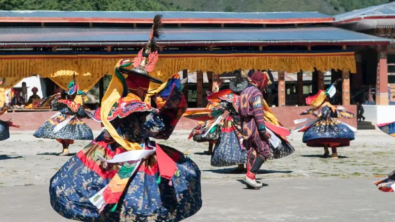 Traditional dancers in colorful costumes perform at the Thimphu Tshechu festival in Bhutan.