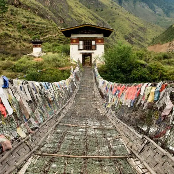 Thimphu in Bhutan - Suspension bridge with prayer flags leading to a traditional Bhutanese house.