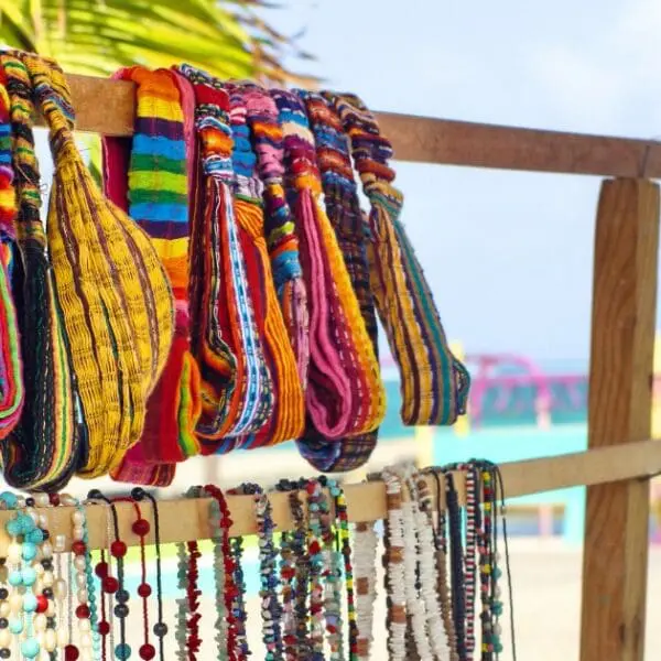 Colorful Belize souvenirs: handmade bags and jewelry on a beach stand.