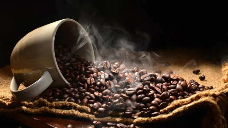 Belize souvenirs: Coffee beans spill from a cup, aromatic and freshly roasted.