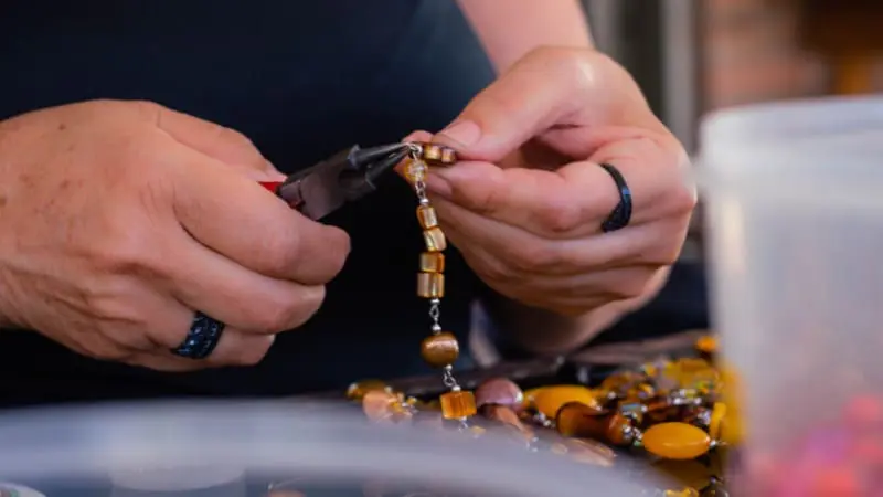 Artisan crafting handmade jewelry, a common Belizean souvenir.