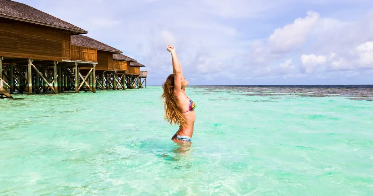 Woman enjoying clear water near overwater bungalows in the Maldives.