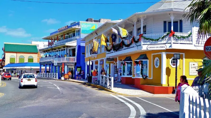 Colorful stores line George Town street with cars and people.