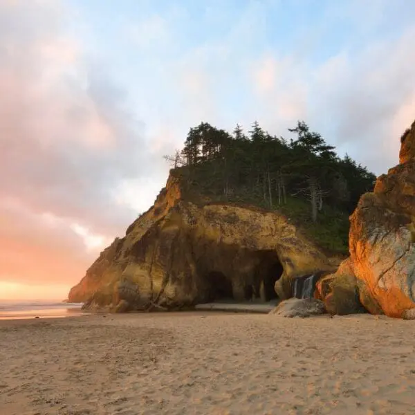 Dramatic sea cave and rock formations at Hug Point Cannon Beach, at sunset.