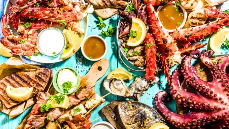 Fresh seafood feast with grilled fish, lobster, and octopus on a turquoise table.