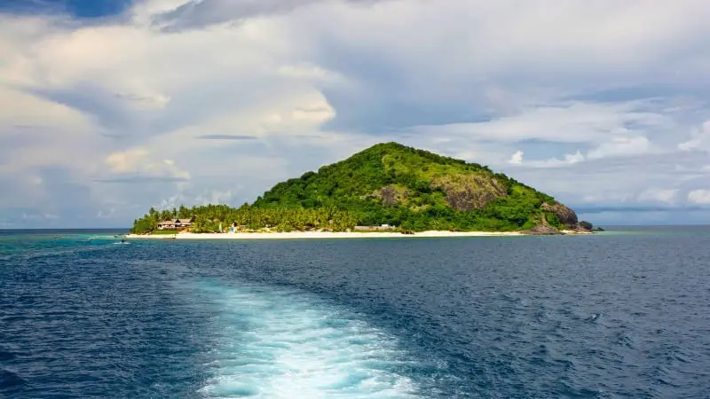 Mamanuca Islands tropical paradise with lush green hill and pristine beach.