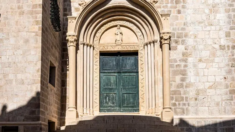 Ornate arched doorway in Dubrovnik's stone walls.