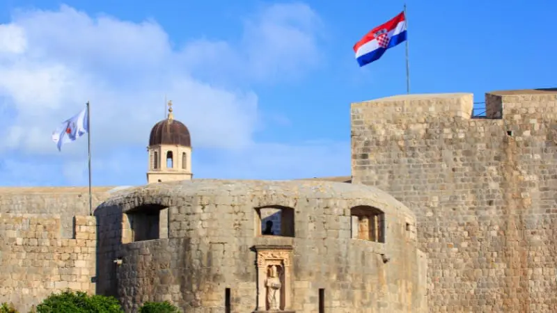 The Croatian flag over Dubrovnik's fortifications shows the city's defensive architecture.