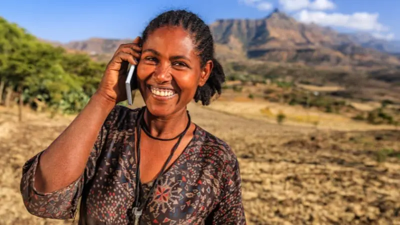 Woman enjoying a call in Aksum, Ethiopia, with scenic mountain views.