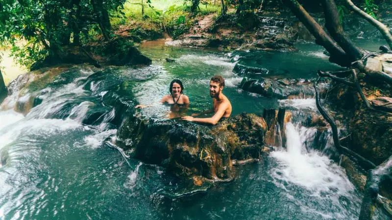 Couple enjoying a natural hot spring bath at Beitou Hot Springs, surrounded by nature.