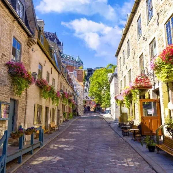Street with the best restaurants in Quebec City with stone buildings and flowers.