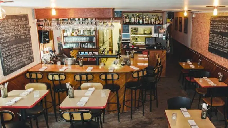 Buvette Scott's space with a wooden bar and chalkboard menu.