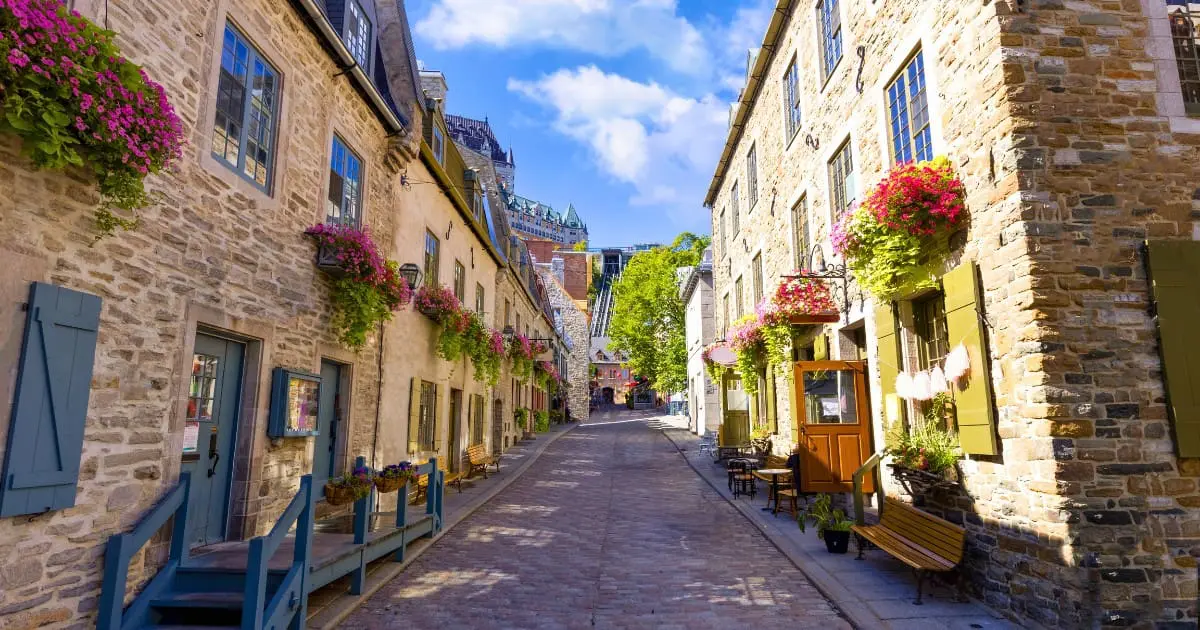 Street with the best restaurants in Quebec City with stone buildings and flowers.
