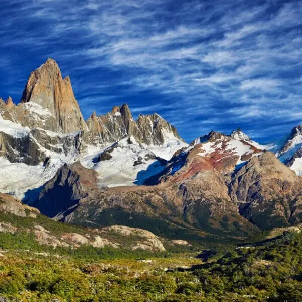 Mounts Fitz Roy has jagged peaks that rise high above green valleys on a clear day.