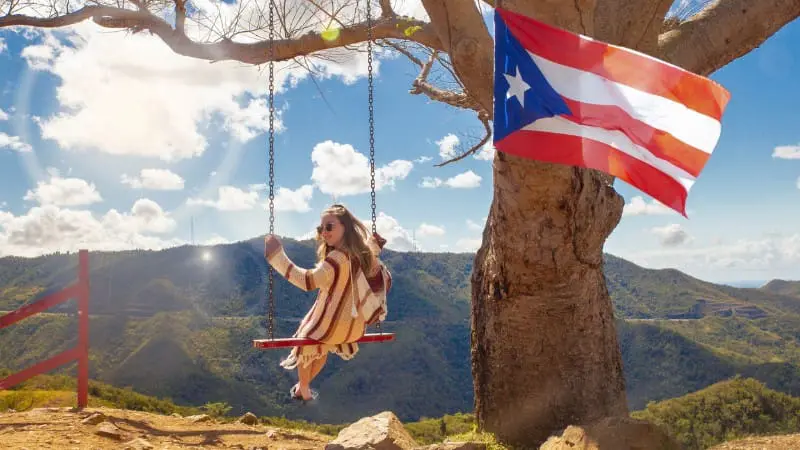 Woman swinging with Puerto Rico flag, a must-see in any Puerto Rico itinerary.