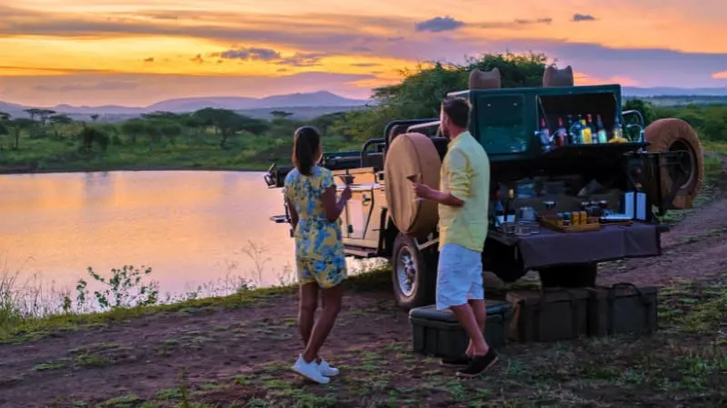 Couple enjoying a sunset with a safari vehicle on a South Africa Itinerary 10 Days.
