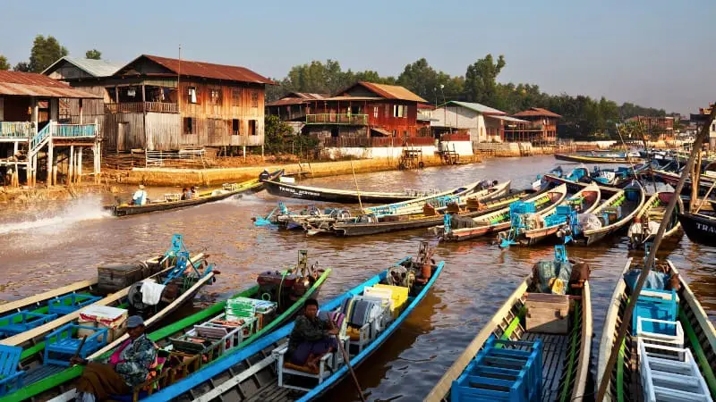 Boats docked by a village at Inle Lake, highlighting water pollution concerns.