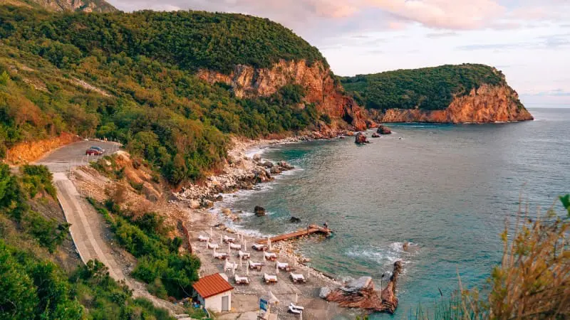 Crvena Glavica Beach in Montenegro, known for its red cliffs and clear water.