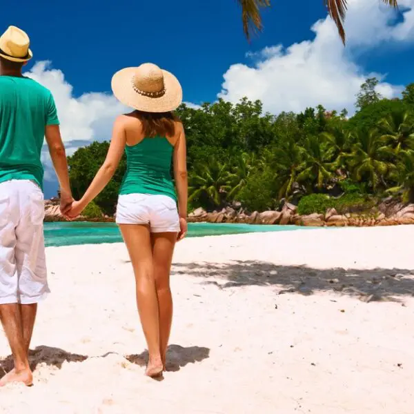 Couples stroll on pristine beaches during their romantic Seychelles honeymoon.