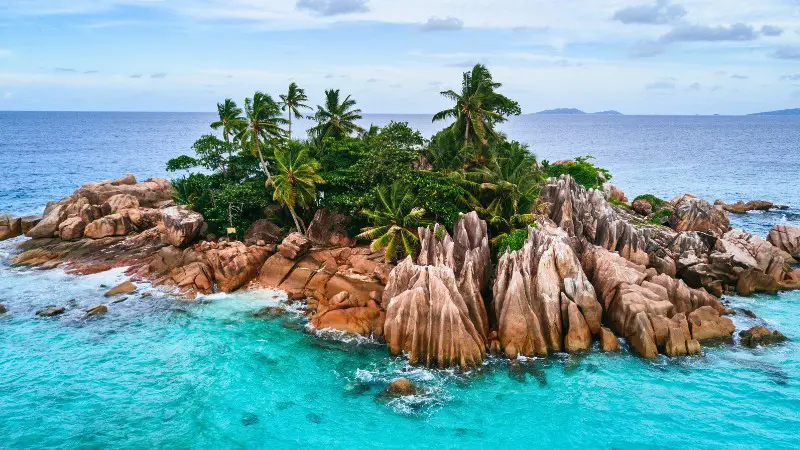 A remote tropical island with granite rocks and palm trees in Seychelles.