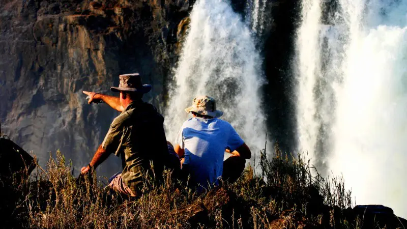 Travelers enjoying the view from a safe distance, a tip for staying cautious at Victoria Falls.