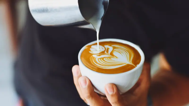 Barista making latte art on a coffee.