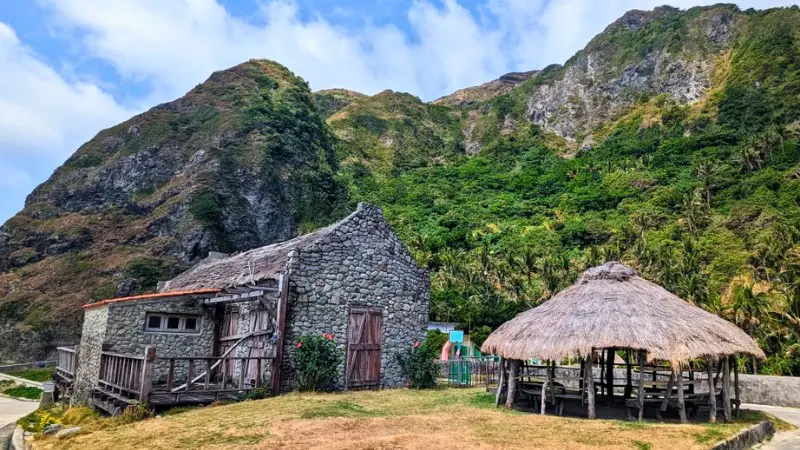 Traditional stone houses in Batanes with scenic mountain backdrop.