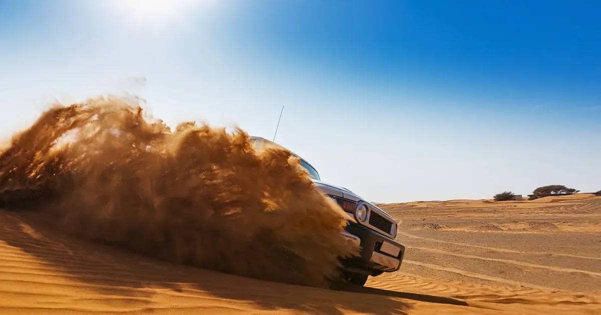 4x4 vehicle creating sand spray on Ajman desert safari dune bashing.