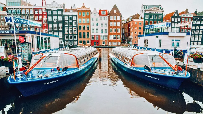 Two canal cruise boats docked in Amsterdam, ready for a city sightseeing tour.
