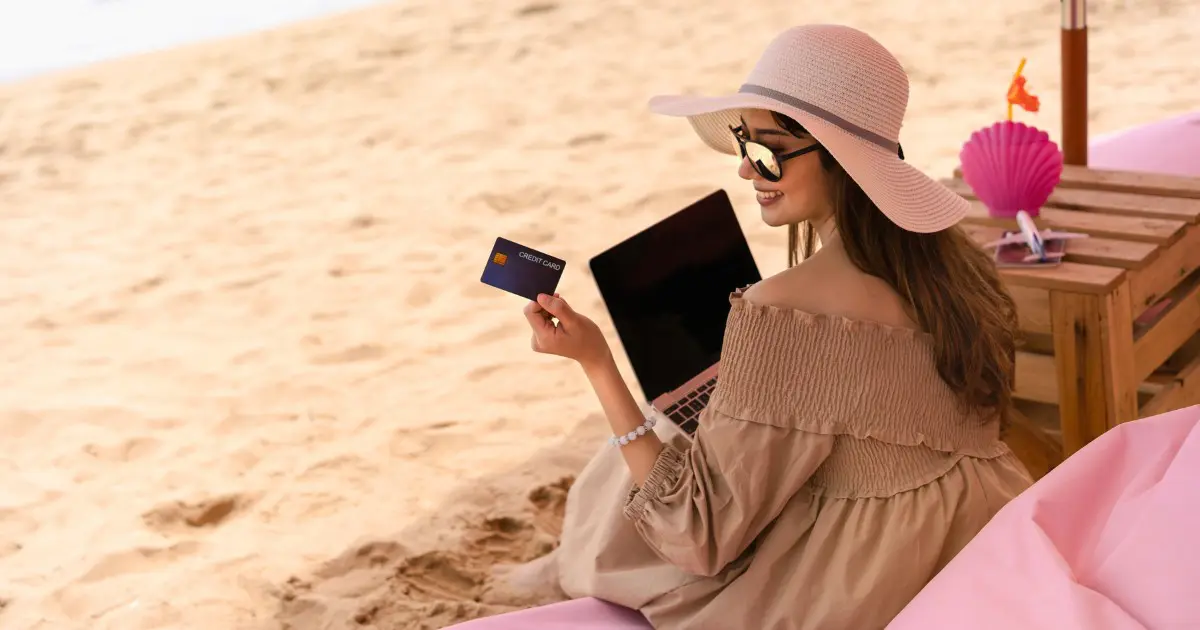 Woman uses travel credit card benefits for beach vacation purchases.