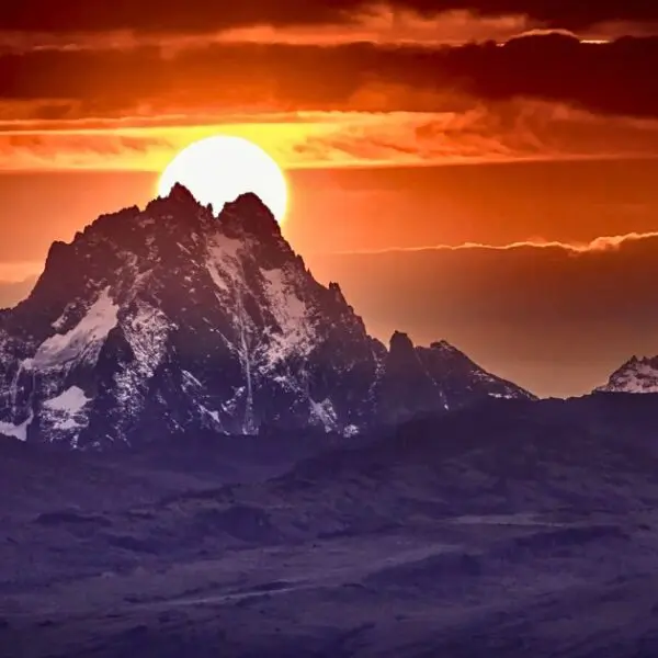 Mt Kenya's jagged peaks silhouetted against dramatic orange sunset sky.