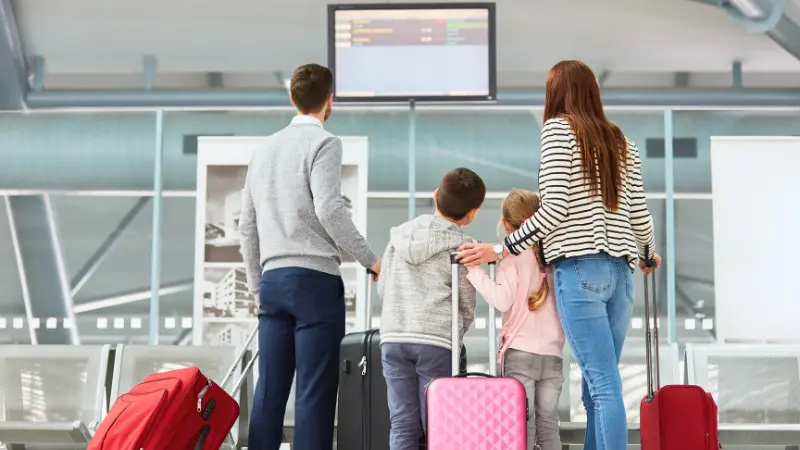 Family checking airline reward program status on departure board.