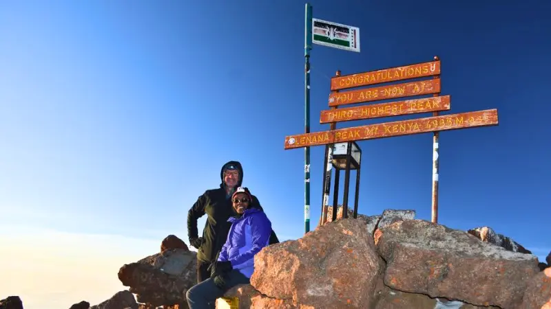 Climbers celebrate reaching Point Lenana's summit marker at 4,985m on Mt Kenya.