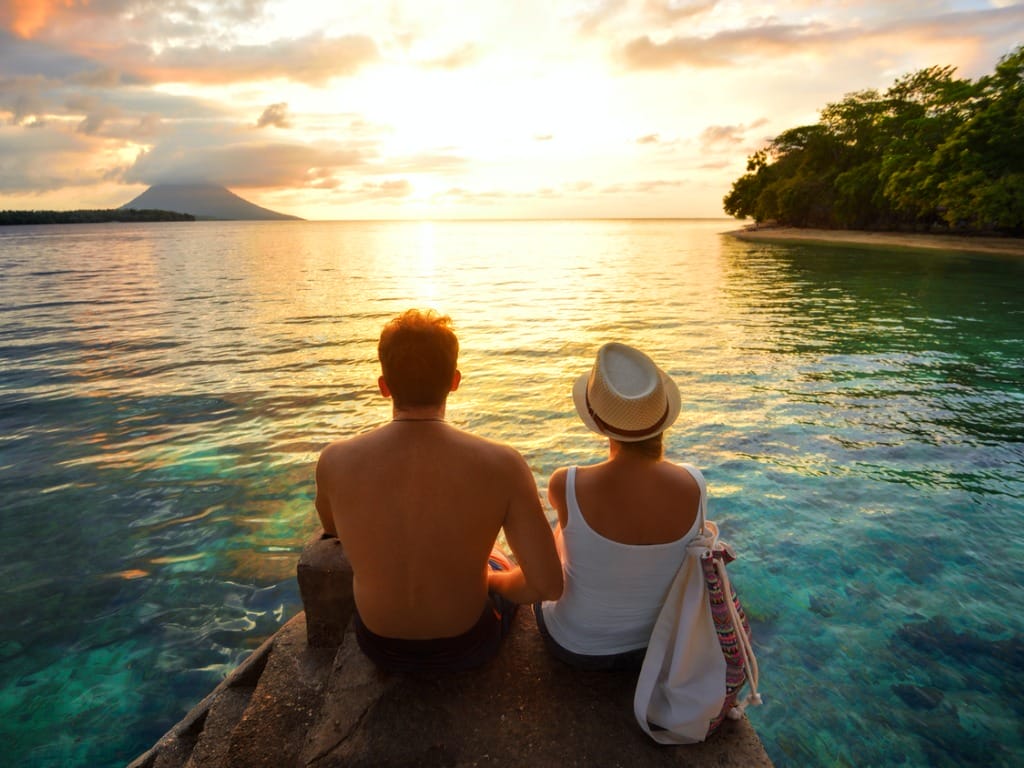 couple sitting on rocks watching sunset