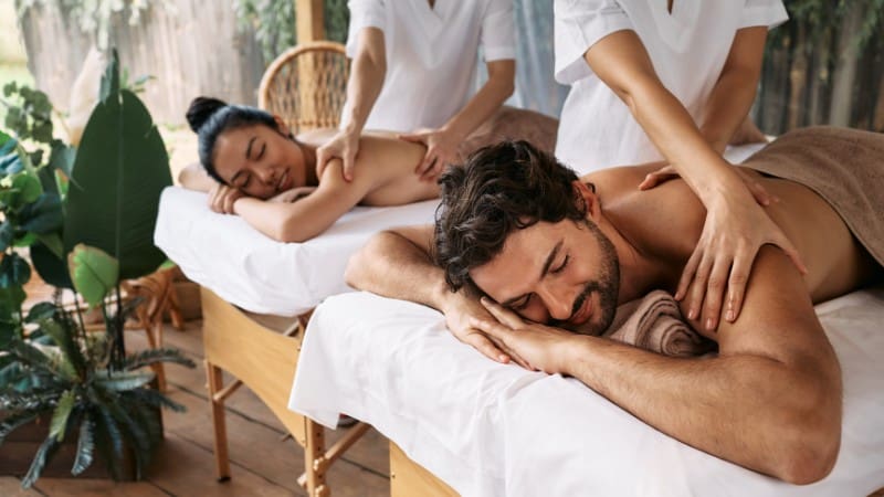 Tourists enjoying a relaxing couples massage at an adults only resort in Fiji, surrounded by lush greenery.