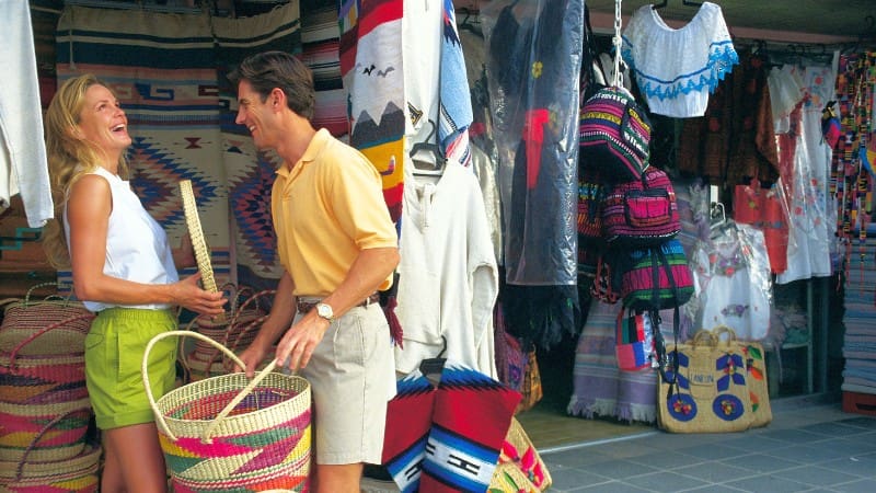 Couple shopping at a colorful market stall, an activity recommended in our extensive guide to traveling Eleuthera.